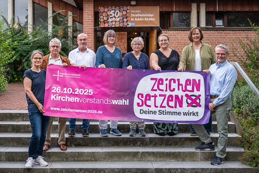 Die Kandidatinnen und Kandidaten der Kirchenvorstandswahl 2025 haben sich am Aufgang zur Kirche zum Gruppenbid aufgestellt.