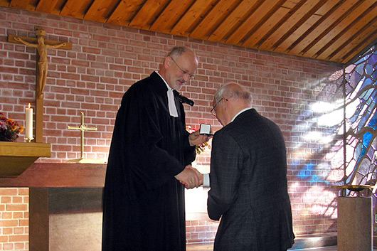 Dr. Bernhard Orlich empfängt die Ehrung durch Dekan Hanns Baumeister vor dem Altar der Trinitatiskirche.
