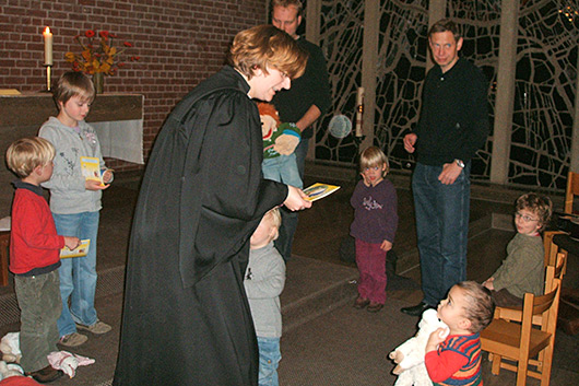 Blick in den Altarraum der Trinitatiskirche, in dem mehrere Kleinkinder, Eltern und Pfarrerin Bettina Mohr zu sehen sind.