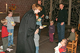 Blick in den Altarraum der Trinitatiskirche, in dem mehrere Kleinkinder, Eltern und Pfarrerin Bettina Mohr zu sehen sind.