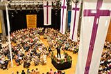 Blick auf die Bhne der Stadthalle in Stadtallendorf, auf der Blserinnen und Blser aus zahlreichen Posaunenchren im Halbkreis sitzend ihre Instrumente spielen.