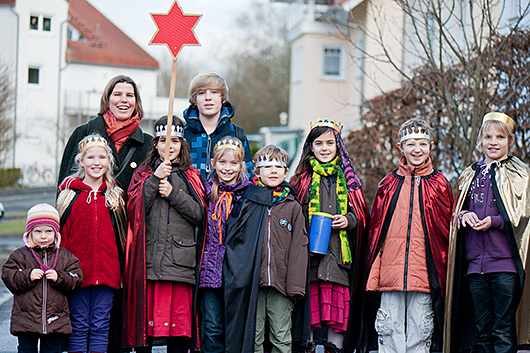 Eine Gruppe von Sternsingern auf der Strae vor einem Haus, in das sie ihren Segen gebracht haben.