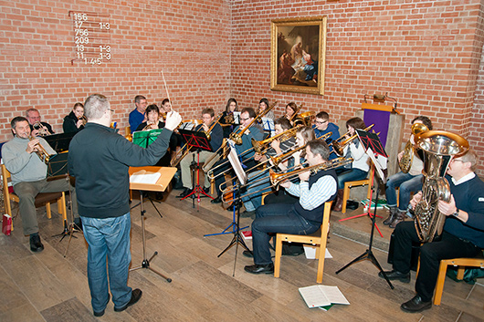 Der Posaunenchor mit Dirigent Marc Multhaupt beim Einspielen im Kirchraum der Trinitatiskirche.