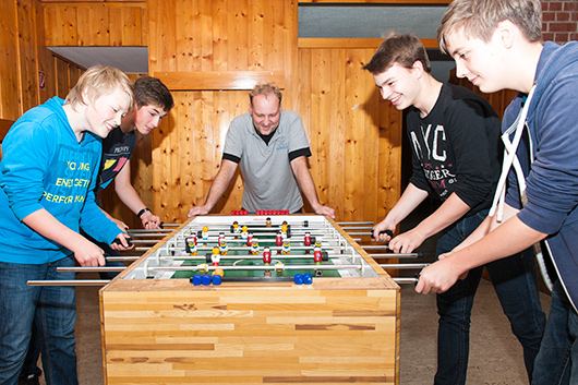 Vier Jugendliche spielen Tischfuball im Untergeschoss der Trinitatiskirche.