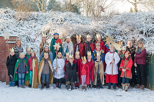 26 Sternsingerinnen und Sternsinger haben sich mit ihren Betreuerinnen und Betreuern im Auenbereich der Trinitatiskirche zum Gruppenfoto aufgestellt.