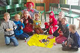 Die Kindergottesdienst-Kinder sitzen im Halbkreis im Kindergottesdienstraum der Trinitatiskirche und blicken freudig in die Kamera.