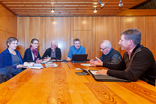 Die Mitglieder der Redaktion sitzen an einer Tischgruppe im groen Gemeinderaum und diskutieren.