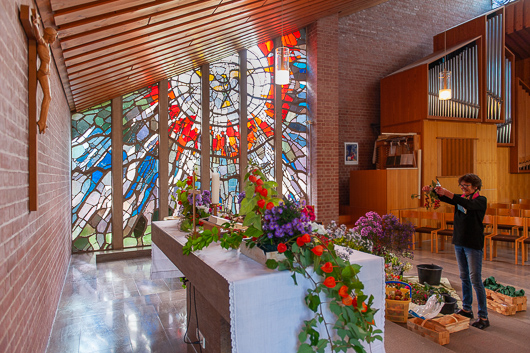 Beate Clasani beim Schmcken des Altars mit dem Pfingstfenster im Hintergrund.