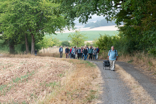 Die Teilnehmerinnen und Teilnehmer beim Wandern auf einem Weg am Waldrand.