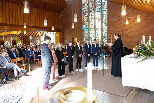 Die Noch-Konfirmandinnen und -Konfirmanden stehen mit dem Rcken zur Gemeinde vor dem Altar, wo Pfarrerin Mohr eine Ansprache an sie hlt.