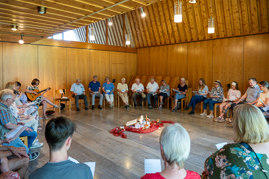 Die Besucherinnen und Besucher des Gottesdienstes sitzen im Kreis und singen.