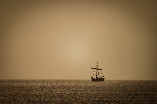Ein in der Ferne erkennbares altertmlich aussehendes Segelschiff fhrt einsam auf dem Stettiner Haff.
