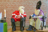 Weihnachtsmann und Nikolaus sitzen auf Sesseln im Altarraum der Trinitatiskirche und unterhalten sich angeregt.