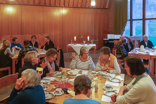 Blick in den groen Gemeinderaum der Trinitatiskirche, wo an Tischen Gottesdienstbesucherinnen und -besucher Platz genommen haben.