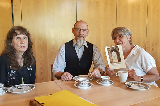 Drei Teilnehmer*innen sitzen nach dem Gottesdienst an einem Tisch im groen Gemeinderaum und unterhalten sich beim Kirchencaf.