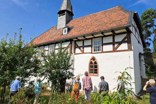 Die Teilnehmerinnen und Teilnehmer des Ausflugs betrachten das uere der Alten Kirche in Brgeln.