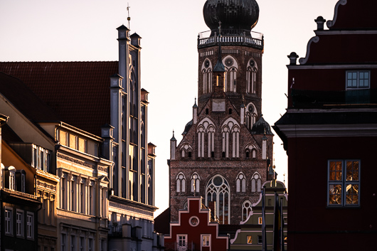 Blick auf einige Giebelhuser der Altstadt und die Ostseite des Greifswalder Doms St. Nikolai im Abendlicht.