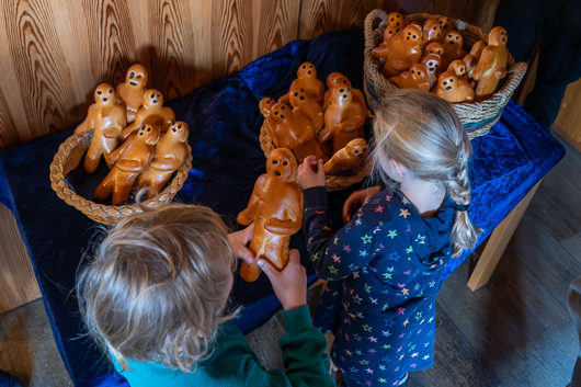 Zwei Kinder sind von hinten im Foyer der Trinitatiskirche zu sehen, wie sie sich aus den mit Weckmnnern gefllten Krben bedienen.
