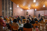 Blick vom hinter in den Kirchenraum: Benedikt Kaloudis steht vor dem Altar und spricht zu den Besucherinnen und Besuchern des Gottesdienstes.