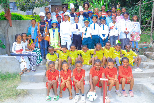 Mehr als vierig Kinder haben sich - gekleidet in typischen Monturen ihrer Traumberufe - zum Gruppenbild aufgestellt. Man sieht Sportler*innen, Fuballer*innen, Musiker*innen, Kch*innen, rztinnen und rzte bzw. medizinisches Fachpersonal, Bauarbeiter*innen und Zivialangestellte.