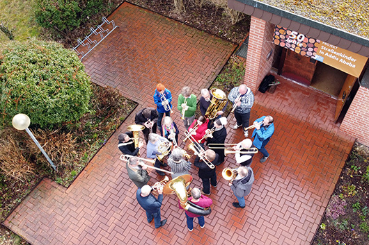Foto aus der Vogelperspektive, das den Posaunenchor der Elisabethkirche spielend vor dem Eingang zur Trinitatiskirche zeigt.