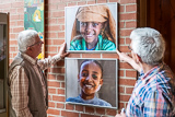 Im Foyer der Trinitatiskirche sind Heinz Rau und Rainer Wagner zu sehen, wie sie zwei bereinander angeordnete Fotos von Kindern des Straenkinder-Projekts ausrichten.