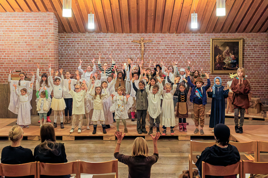 Die teilnehmenden Kinder am Krippenspiel 2025 haben zur bewegten Begleitung des eigenen Gesangs ihre Arme in die Höhe gereckt.