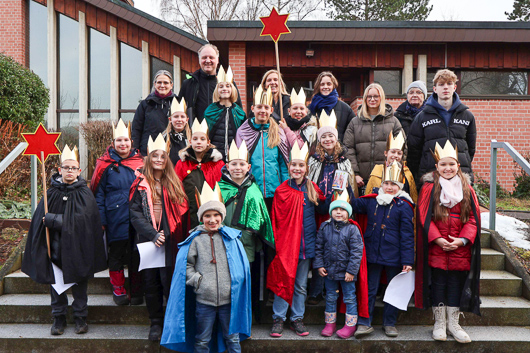 Die Sternsinger-Kinder haben sich mit Betreuerinnen und Betreuern zum Gruppenbild auf der Treppe vor der Trinitatiskirche aufgestellt.