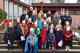 Die Sternsinger-Kinder haben sich mit Betreuerinnen und Betreuern zum Gruppenbild auf der Treppe vor der Trinitatiskirche aufgestellt.