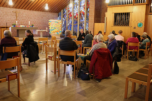 Blick in die Trinitatiskirche, wo Kleingruppen von Gottesdienstbesucherinnen und -besuchern sich sitzend um Tische gruppiert haben.