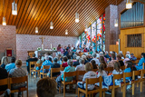 Blick von hinten in die Trinitatiskirche, wo der Projektchor vor dem Pfingstfenster beim Singen zu sehen ist.