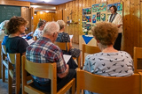 Blick in den Kindergottesdienstraum im Untergeschoss der Trinitatiskirche, wo Lektorin Birgit Heeßel am Pult zu sehen ist.
